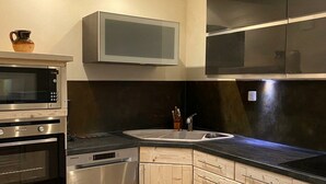 A modern kitchen with built-in appliances, a black countertop, and wooden cabinetry.