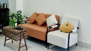 A living room with a sofa, a chair, a small wooden table, and a wall-mounted light fixture. - Homestay Da Lat - The November Stay - Ngo Quyen (Cam Ly - Da Lat)