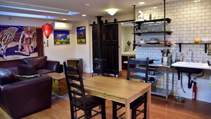 A modern living room with a fireplace, dining area, and kitchen with white tiled backsplash.