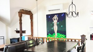 A dining area with a long table, chairs, a wooden bench, and a painting on the wall.
