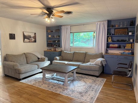 A cozy living room with a sectional sofa, a wooden coffee table, and a blue shelving unit filled with decorative items.