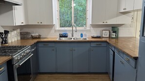 A kitchen with a built-in stove, a sink, and a window with a view of greenery. - Darbonne Ranch House - 12 beds! (Farmerville)