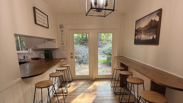 A kitchen with a wooden countertop, a bar area with stools, a hanging light fixture, and a door leading outside. - Darbonne Ranch House - 12 beds! (Farmerville)