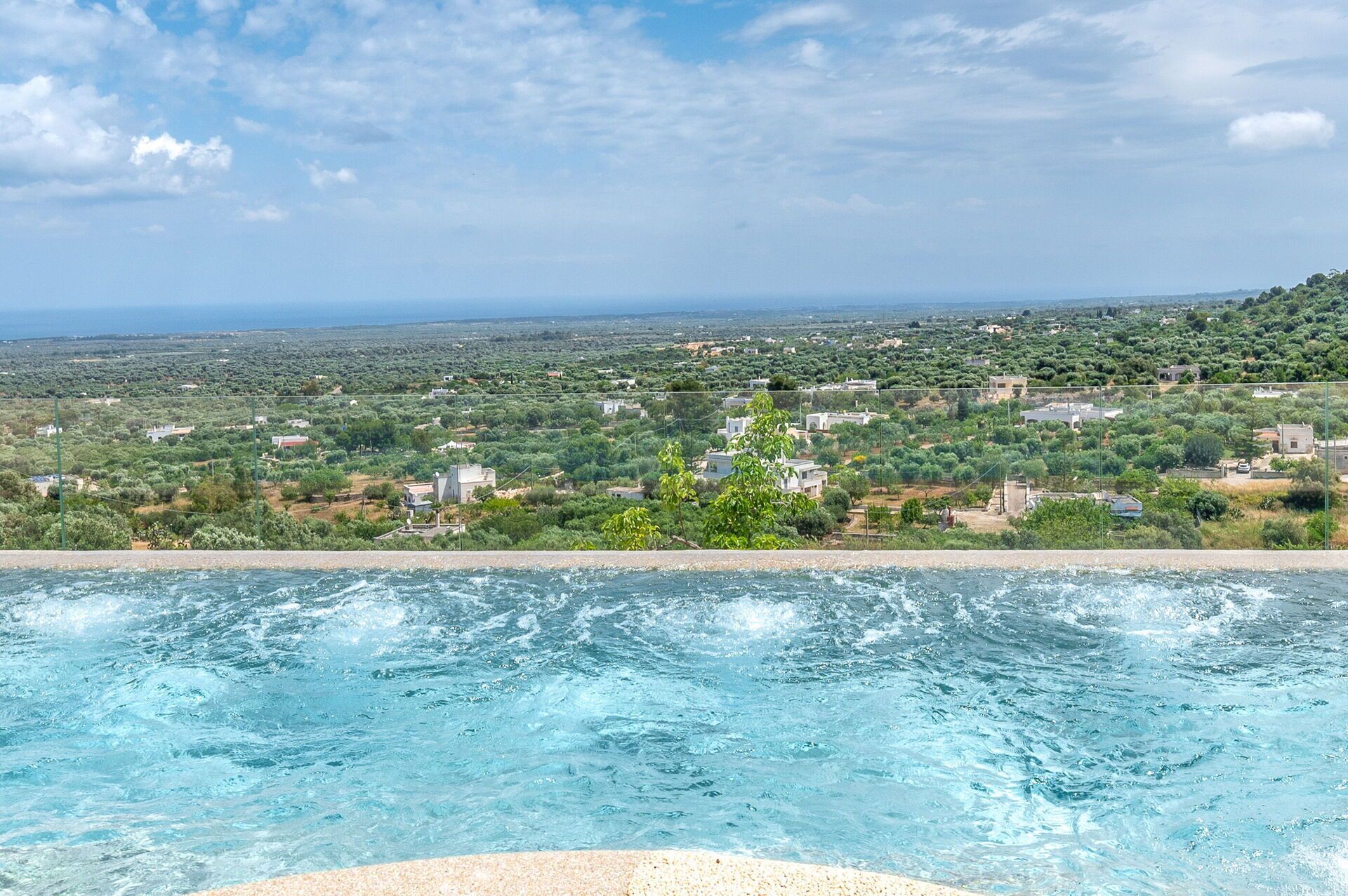 A swimming pool with a view of a coastal landscape and buildings.