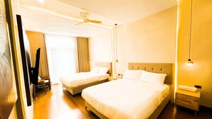 Habitación de hotel con dos camas, un ventilador de techo, una mesita de noche y un escritorio.