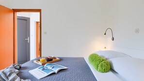 A neatly arranged hotel room with a bed, a bedside table with a tray of breakfast, a reading area with a magazine, and a green throw pillow. - Apartman Marko by Villas Guide (Medulin)