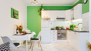 A modern kitchen with white cabinets, a built-in oven, and a dining area with a table set for two.