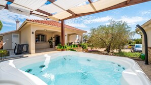 Un jacuzzi en un espacio exterior cubierto con una casa al fondo.