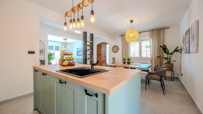 A modern kitchen with a central island, a dining area with a table and chairs, and a living space with a sofa.