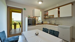 A compact kitchen with a dining area, a view through the door, and a small window. - Villa Panorama Hill by Villas Guide (Cestica)