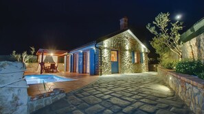 A stone building with a pool, outdoor seating, and a stone wall.