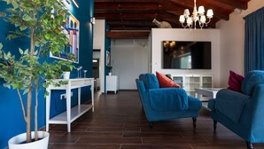 Un salon moderne avec un canapé bleu, une plante en pot, un téléviseur à écran plat et un plafond en bois.