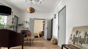 A spacious living room with a large armchair, a hanging light fixture, and a painting on the wall. - MAISON ART COLLECTION (Essaouira)