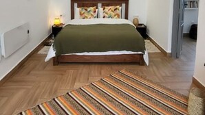 A bedroom with a wooden bed, a green blanket, a patterned rug, and two bedside lamps. - MAISON ART COLLECTION (Essaouira)