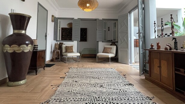 A spacious room with a large rug, a decorative vase, and a chandelier. - MAISON ART COLLECTION (Essaouira)