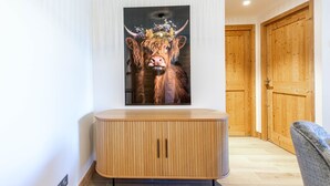 Un intérieur moderne avec un meuble en bois, une œuvre d’art encadrée représentant un taureau et des portes en bois.