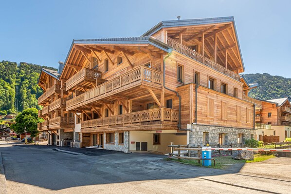 A multi-story wooden building with balconies and a stone base, located in a mountainous area.