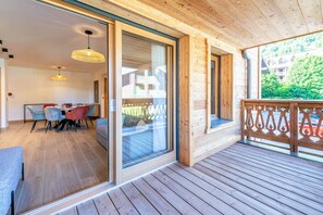 A wooden deck with a glass door leading to a dining area with a table and chairs.
