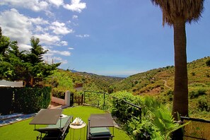 Une terrasse avec deux chaises longues, une petite table et une vue sur un paysage vallonné.