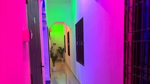A narrow hallway with a tiled floor, a potted plant, and a door on the left. - JP Hotel (Tezpur)