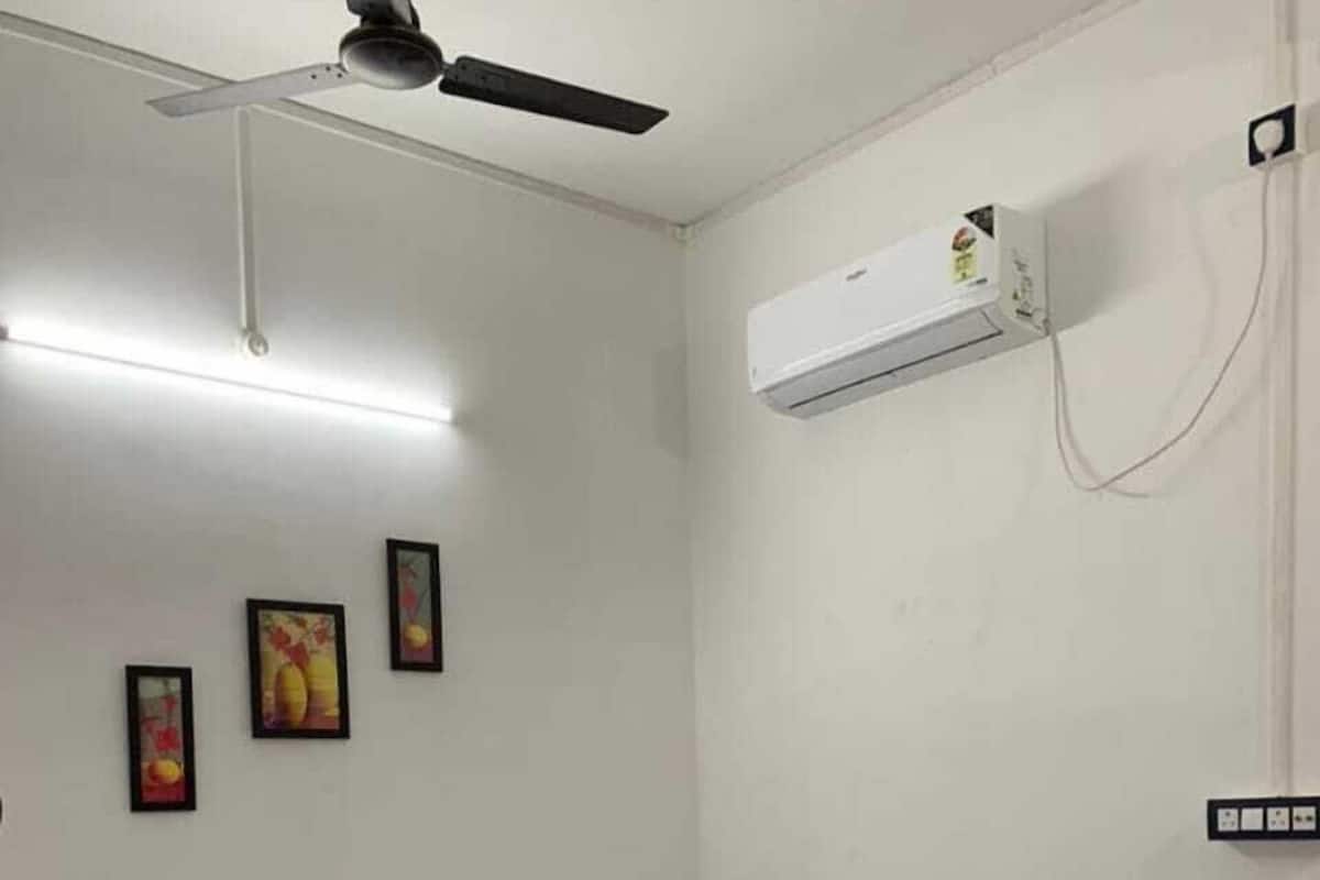 Ein Schlafzimmer mit einem Bett, einem Deckenventilator, einer Klimaanlage und drei gerahmten Bildern an der Wand.