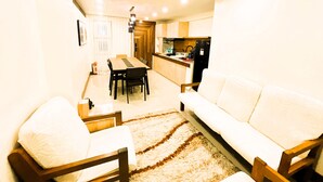 Una sala de estar con sofá, sillas, una mesa de comedor y una zona de cocina con armarios y electrodomésticos.