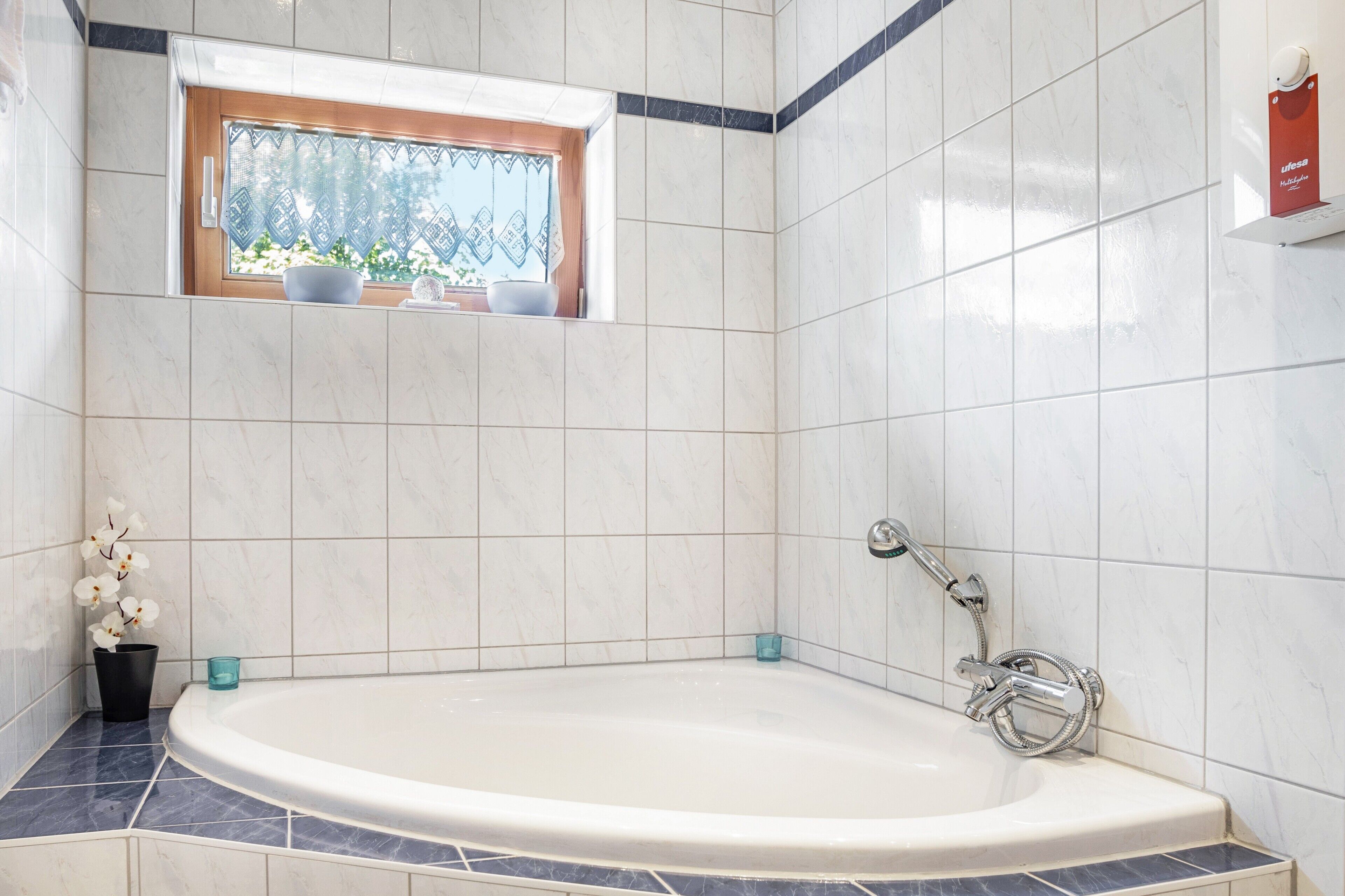A bathroom with a bathtub, a window with a view, and a towel rack.