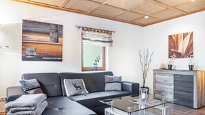 A modern living room with a sectional sofa, a glass coffee table, a wooden cabinet, and abstract wall art.