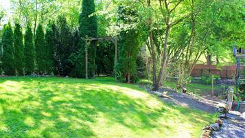 A garden with a pergola, trees, and a brick wall.