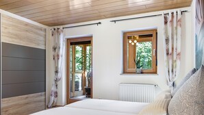 A bedroom with a bed, curtains, a window, a radiator, and a plant.