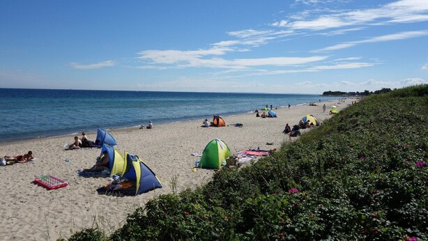 A beach with tents and people relaxing. - Apartment 'Block' with Private Terrace, Shared Garden and Wi-Fi (Brodersby OT Schönhagen)