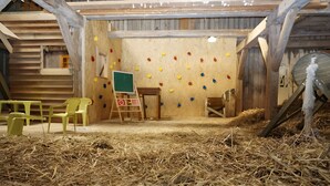 A rustic room with a climbing wall, a chalkboard, and hay on the floor. - Apartment 'Block' with Private Terrace, Shared Garden and Wi-Fi (Brodersby OT Schönhagen)