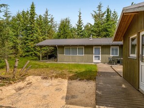 A single-story cabin with a metal roof, a front porch, and a deck.