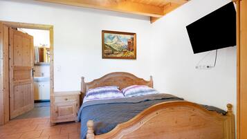 A wooden bed with a headboard, a painting on the wall, and a television mounted on the wall.