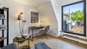 Una habitación moderna con escritorio, silla y ventana grande.