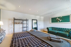 A bedroom with a bed, a green sofa, a wall-mounted coat rack, and a framed picture. - Apartment 'My Cocoon' with Private Terrace and Wi-Fi (Lüdenscheid)