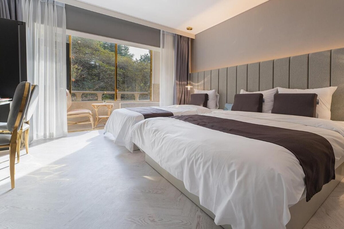 A modern bedroom with a large bed, a desk, and a chair.