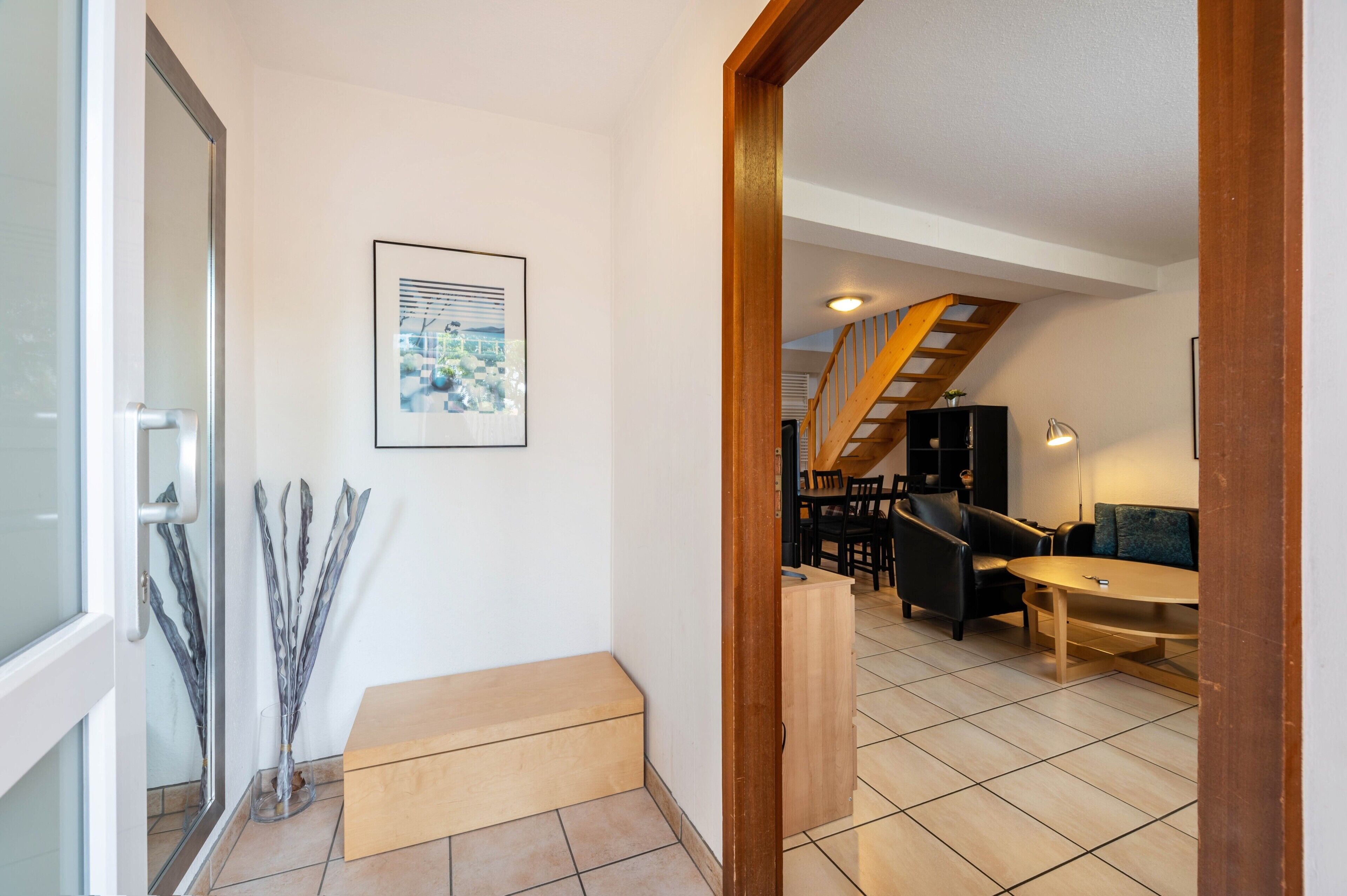 Un pasillo que conduce a una sala de estar con una escalera, un sofá y una mesa de centro.