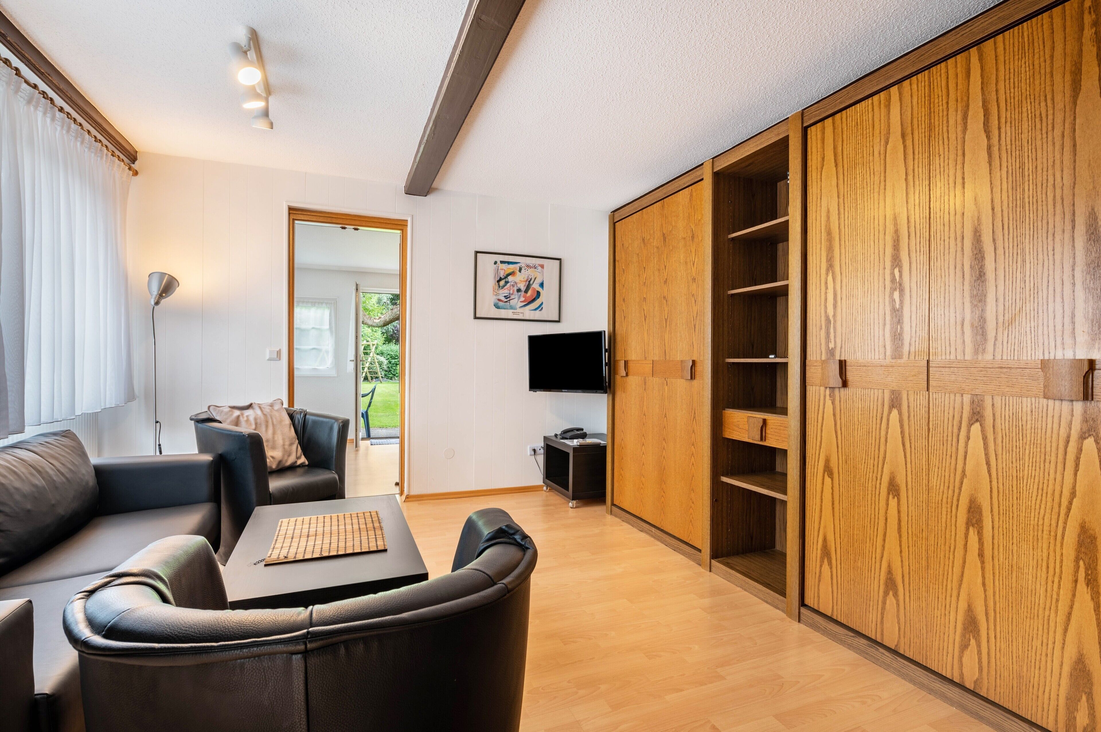 Een moderne woonkamer met een bank, een salontafel, een televisie en een houten garderobe.