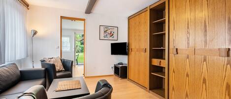 Een moderne woonkamer met een bank, een salontafel, een televisie en een houten garderobe.