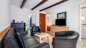 A modern living room with a sofa, chairs, a coffee table, a TV, and a wooden cabinet.