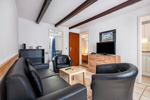 A modern living room with a sofa, chairs, a coffee table, a TV, and a wooden cabinet.