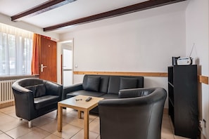 A living room with a sofa, armchair, and a small table with a remote control.