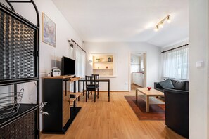 A modern living room with a dining area, a black sofa, a TV, and a small table. - Hus achtern Diek Cuxhaven Apartment No. 04 (Cuxhaven)