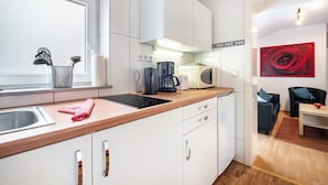 Una cocina moderna con ventana, armarios blancos, cafetera y microondas.