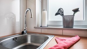 Una cocina con un lavamanos de acero inoxidable, un grifo, una ventana con vistas y una toalla rosa en la encimera.