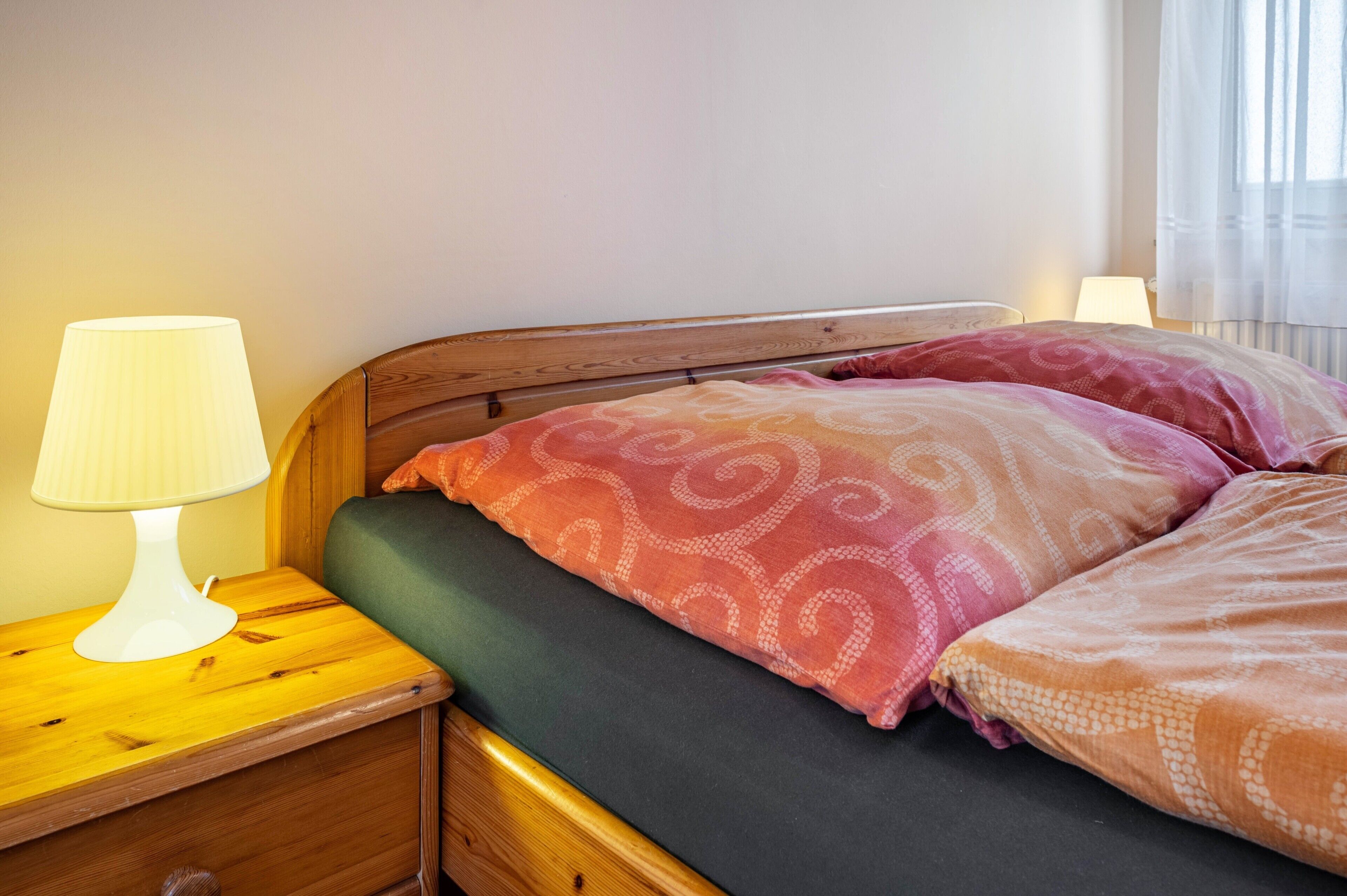 A bed with patterned pillows, a bedside lamp, and a wooden headboard.