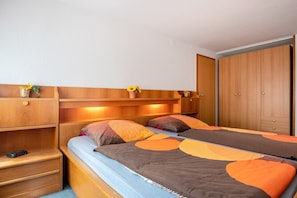 Une chambre à coucher comprenant un lit, des tables de chevet, une armoire et une étagère avec une plante.