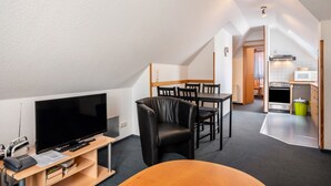 Ein kompakter Wohnbereich mit Fernseher, Sitzgelegenheit, einer Küchenzeile und einem Essbereich.