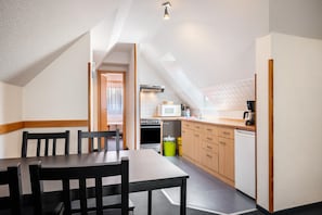 Une cuisine compacte comprenant un coin repas, un four à micro-ondes, une cuisinière et un lave-vaisselle.